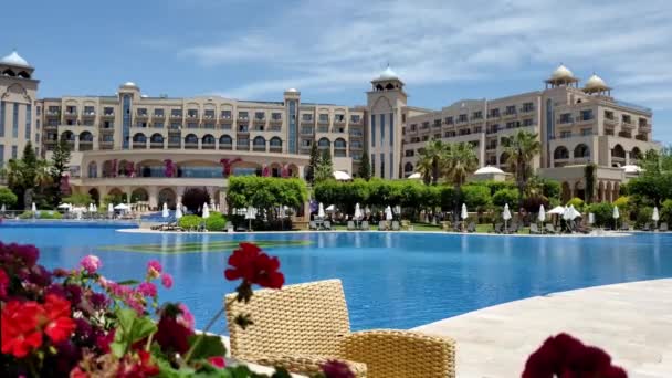 Terraza con vistas al mar con flores de geranio rojo y muebles de ratán en la piscina del complejo de lujo — Vídeo de stock