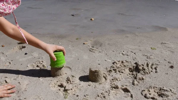 Дитяча рука робить пісочний замок з інструментом для піщаної форми — стокове фото