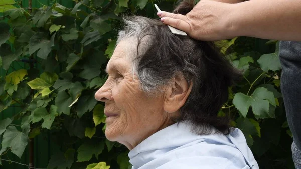 Female hands cutting senior woman hair at backyard — Stok fotoğraf