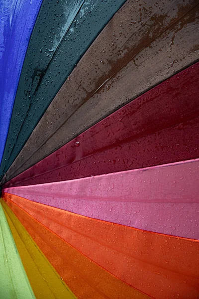 Gotas de lluvia en el colorido paraguas del arco iris primer plano textura de tela húmeda — Foto de Stock