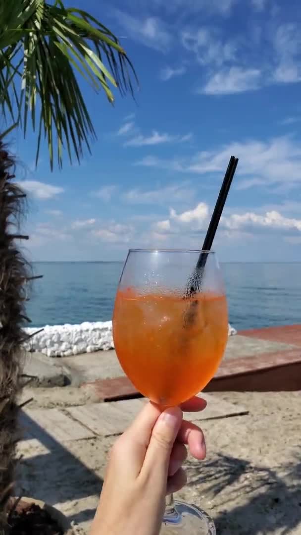 POV літній коктейль Aperol Spritz в склянці з підробленим виноградником, що тримається жіночою рукою — стокове відео