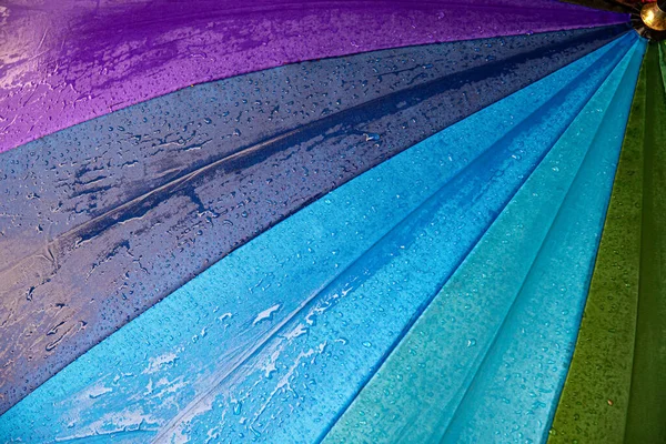 Raindrops on blue purple shades umbrella closeup wet fabric texture