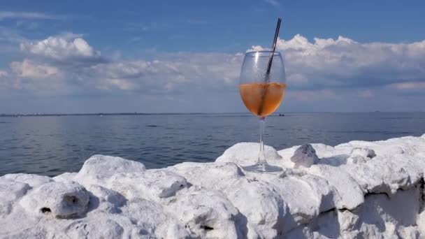 Verre à cocktail panoramique sur une clôture en pierre blanche au bord de la mer avec fond de vagues de mer — Video