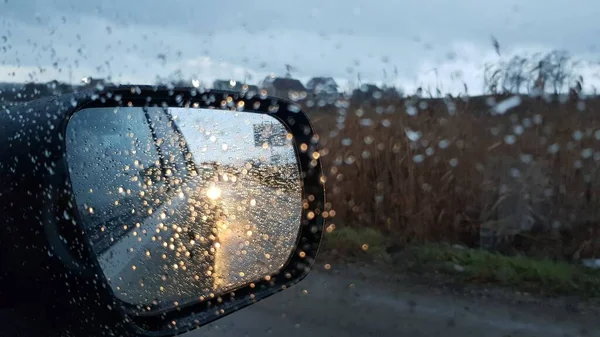 Shot přes mokré auto okno s bočním zrcátkem v podzimním deštivém počasí — Stock fotografie