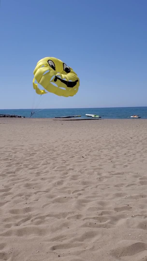 Vertikales Video vom Sommerstrand mit gelbem Parasailing-Flügel, der im Wind fliegt — Stockvideo