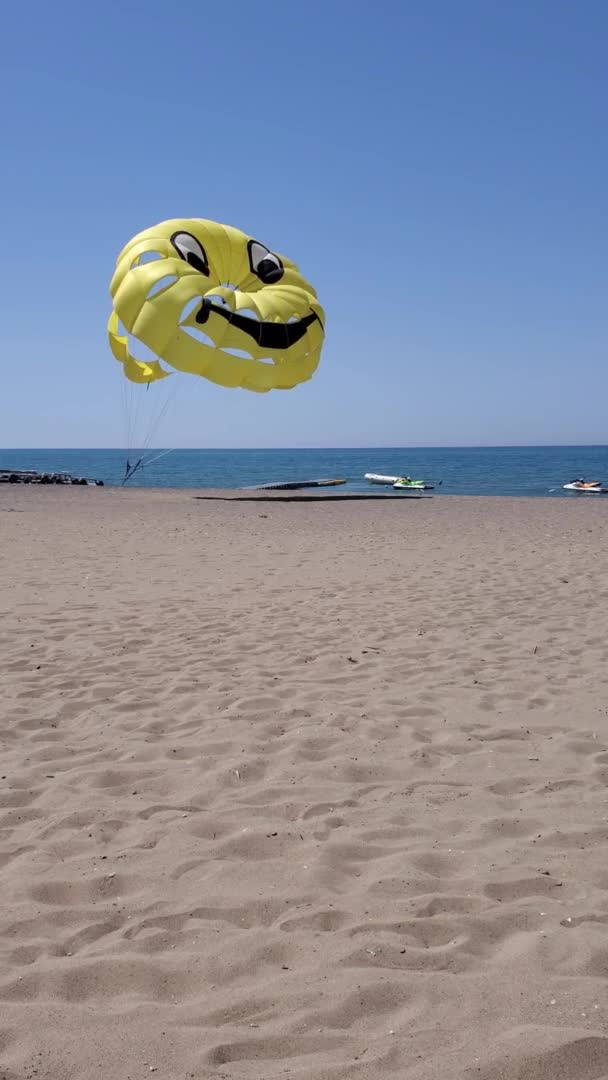 Вертикальний формат відео літнього пляжу з жовтим парасейлінговим крилом, що летить у вітрі — стокове відео