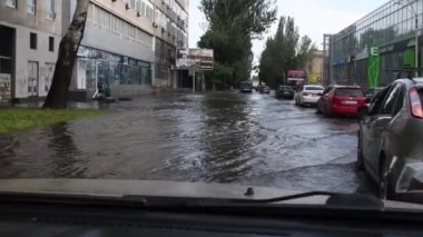 Şehir trafiğinin sel baskınında ön cam manzarası. Su basmış caddelerde arabalar hareket ediyor