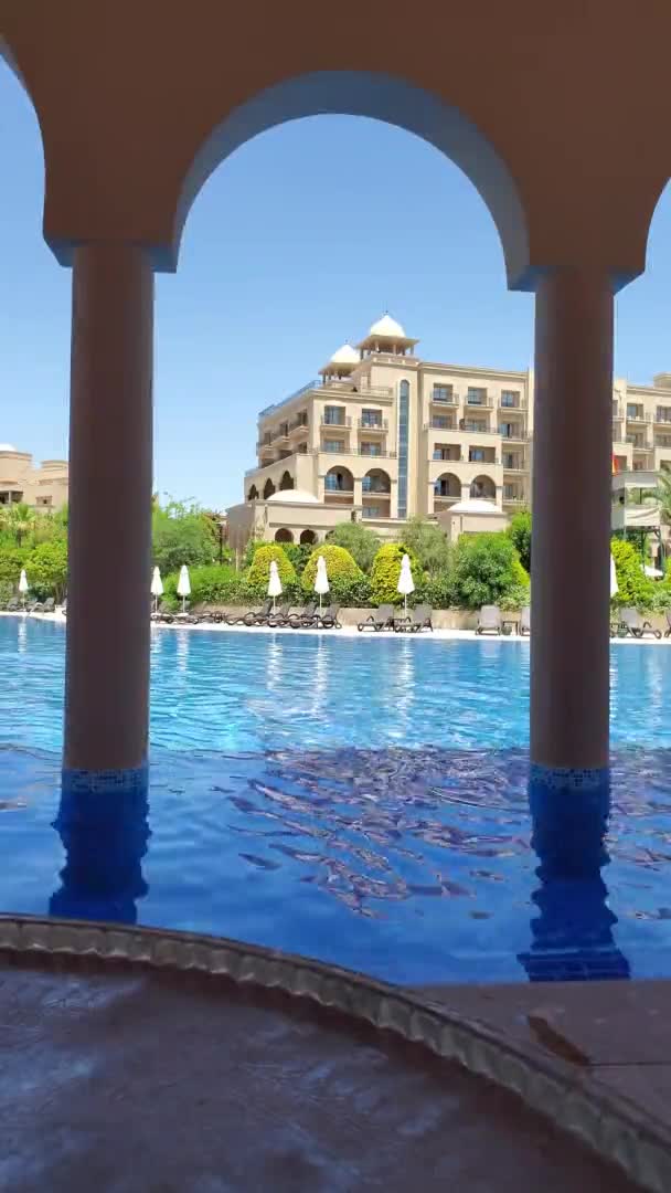 Vítr zvlnění bazén vody v luxusním letovisku na břehu bazénu s arabským stylu oblouku — Stock video