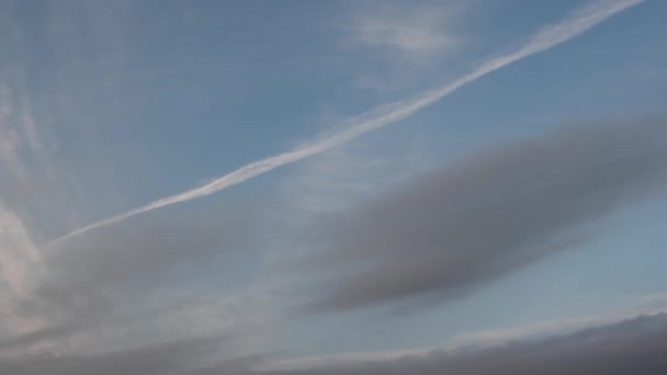 Grijze draaiende wolken en contrail in de schemerige blauwe lucht — Stockvideo