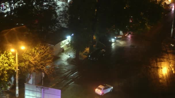 Вид на нічне місто після дощу з розмитими вогнями вуличні ліхтарі та рідкісні автомобілі, що проходять повз — стокове відео