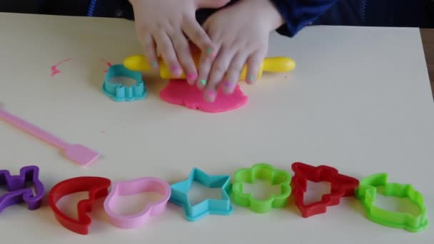 Handen van het kleine meisje 3-5 jaar oud spelen roze deeg met plastic mallen — Stockvideo