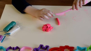 Bebek eller renkli oyun hamuru plastik kalıplar ve killi plastik bıçakla oynuyor.