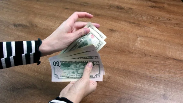 Kadın eli, ahşap arka planda fotokopi alanı olan dolarları sayar