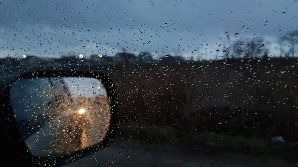 雨の日にサイドミラーで濡れた車の窓を通して撮影 ストックフォト