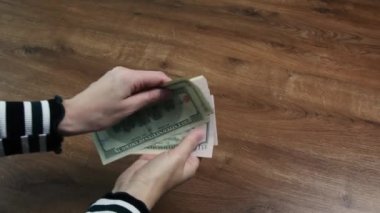 Kadın elleri dolar banknotlarını fan şeklinde tutar ve hasarlı banknotları inceler.