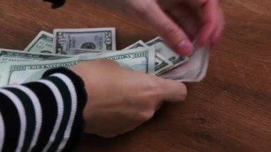 Kadın eli dolar sayar ve uygun olmayan banknotları inceler.