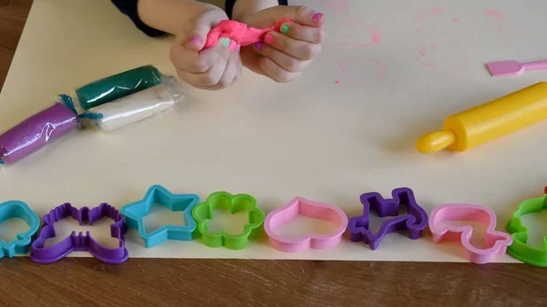 Toddler hands playing colorful play tough with plastic molds and rolling pin — стоковое фото