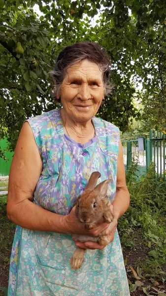 80s vovó envelhecida com coelho de estimação no jardim da fazenda — Fotografia de Stock