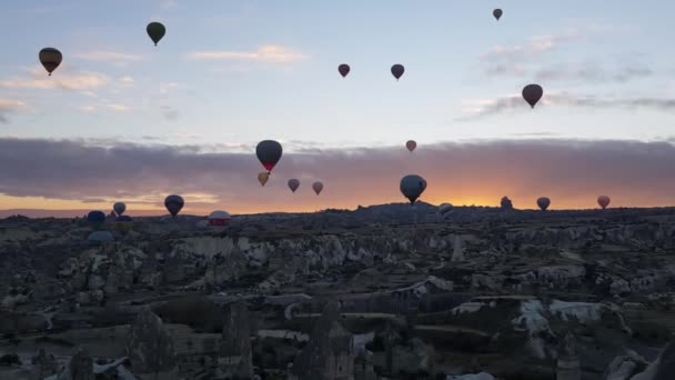 Zonsopkomst en heteluchtballonnen vliegen over berglandschap in Cappadocia Turkije — Stockvideo