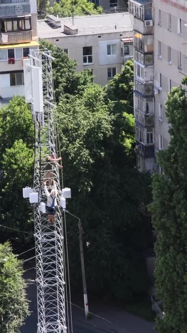 Trabalhadores da construção da torre de comunicação instalam antena em alta base — Vídeo de Stock