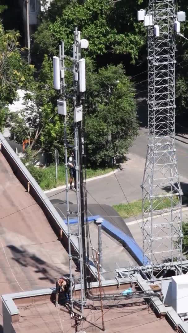 Trabajadores irreconocibles en la azotea del edificio con torre de comunicación — Vídeos de Stock