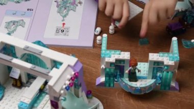 Bebek el masaya oyuncak lego blokları koyar ve Donmuş Disney kalesiyle oynar.