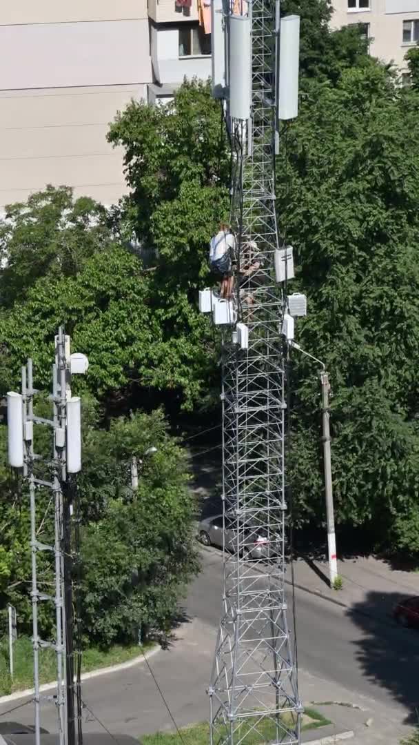 Pracovníci stavby časoměrné věže instalují rádiovou jednotku a antény na horní část konstrukce — Stock video