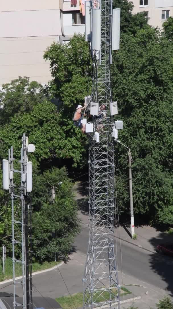 Byggnadsarbetare i torn installerar radioutrustning och antenner ovanpå konstruktionen — Stockvideo