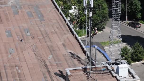 Trabajadores de la construcción instalan unidad de radio y antenas en la parte superior de la estructura — Vídeos de Stock