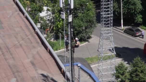 Trabajadores de la construcción instalan unidad de radio y antenas en la parte superior de la estructura — Vídeo de stock