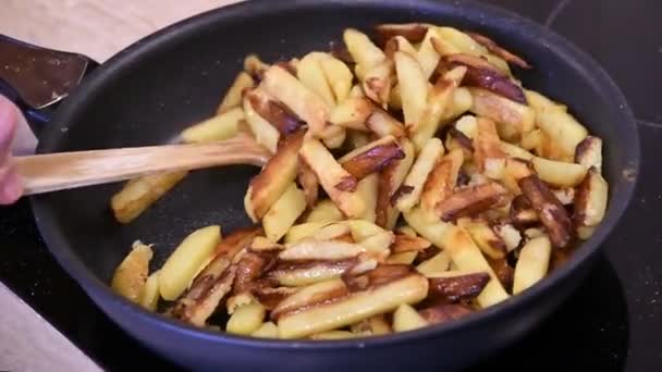 在厨房的炉灶上把自制的炸薯条放在锅里烤和搅拌 — 图库视频影像