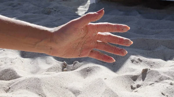 Weibliche Handpalmenhaut bedeckt von Sandkörnern am Strand — Stockfoto