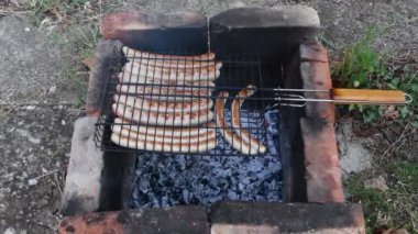 Kömür ve ızgara ızgara ızgara sosisle birlikte yerde taş kırması bir ocak.