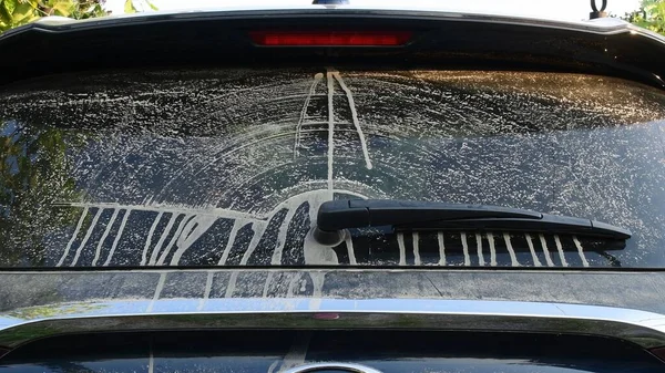 Dirty rear window of car after driving by dirt desert road