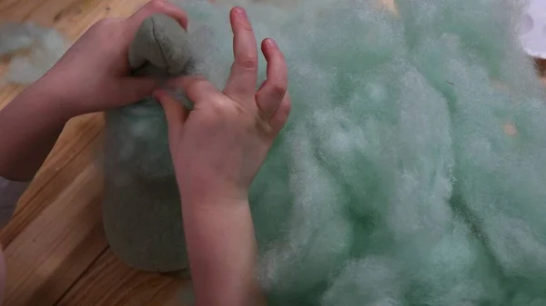 Mãos de criança fazem brinquedo de pelúcia usando enchimento de algodão oco sinterizado — Fotografia de Stock