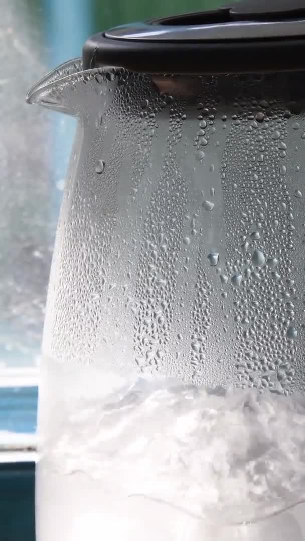 Wrząca woda wewnątrz przezroczysty czajnik w pobliżu okna kuchni — Wideo stockowe
