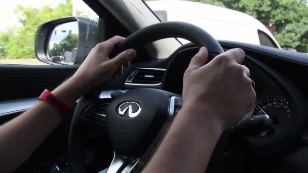 Anak muda tangan memegang roda kemudi Infiniti QX50 saat mengemudi dengan jalan raya — Stok Video