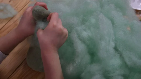 Mãos de criança fazem brinquedo de pelúcia usando enchimento de algodão oco sinterizado — Fotografia de Stock