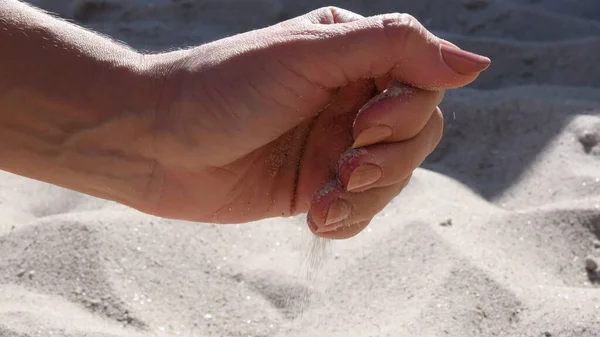 Weibliche Hand hält Sand am Strand — Stockfoto