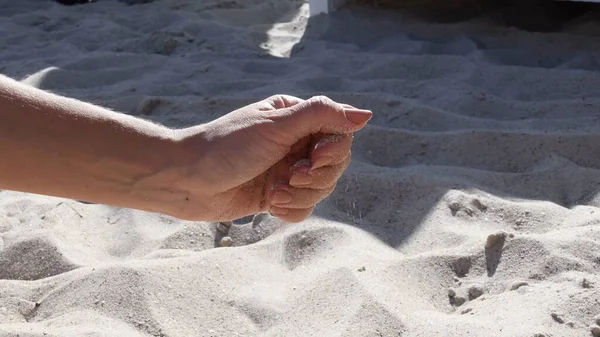 Weibliche Hand verschüttet Strand-Sand aus Handvoll — Stockfoto
