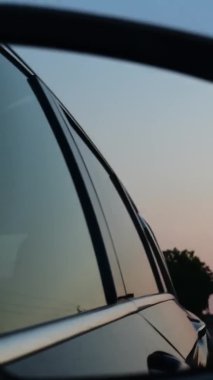 Alacakaranlıkta giden arabanın yan aynadaki yansıması.