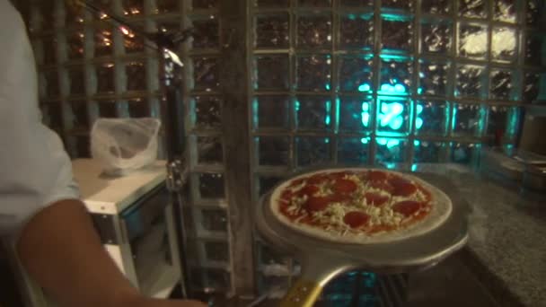 Chef met une pizza au four 