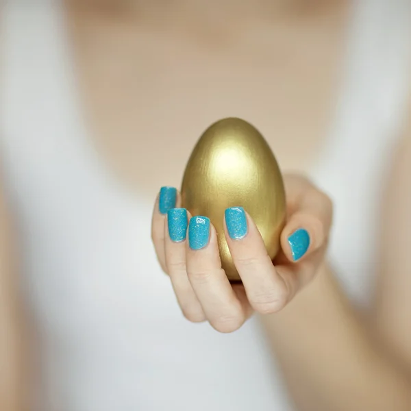 Manos de mujer sosteniendo huevo dorado — Foto de Stock