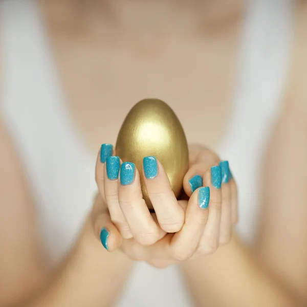 Mulher mãos segurando ovo dourado — Fotografia de Stock