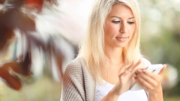 Mooie vrouw met mobiele telefoon in de tuin — Stockvideo