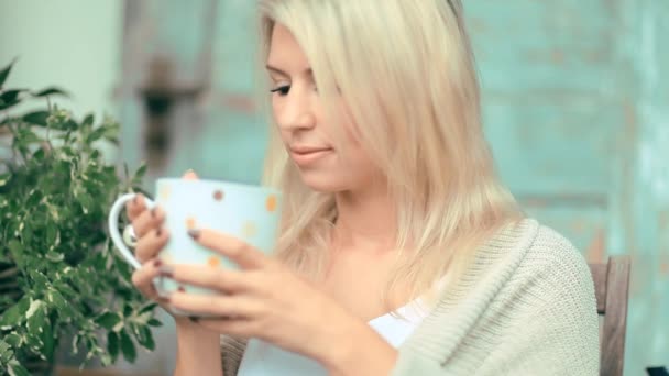 Beautiful, blonde young woman drinking tea in the garden — Stock Video