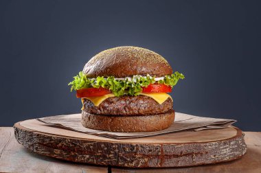 Avustralya ekmeğinde servis edilen lezzetli hamburger. Tahta masa ve gri arka plan. Boşluğu kopyala