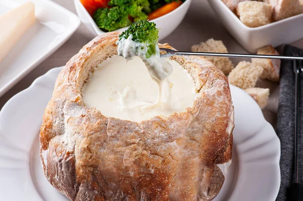 Creamy cheese fondue inside Italian bread. Fork watering brocolis in cream cheese