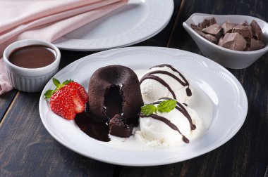 Beyaz tabakta dondurma ve çilekli Petit Gateau.