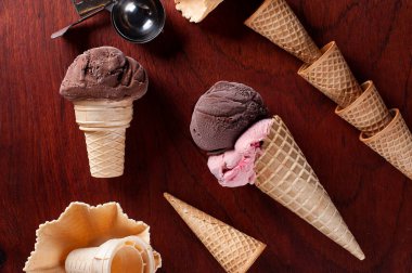 Ahşap arka planda waffle külahında çilekli ve çikolatalı dondurma kompozisyonu. Uzayı kopyala Üst görünüm